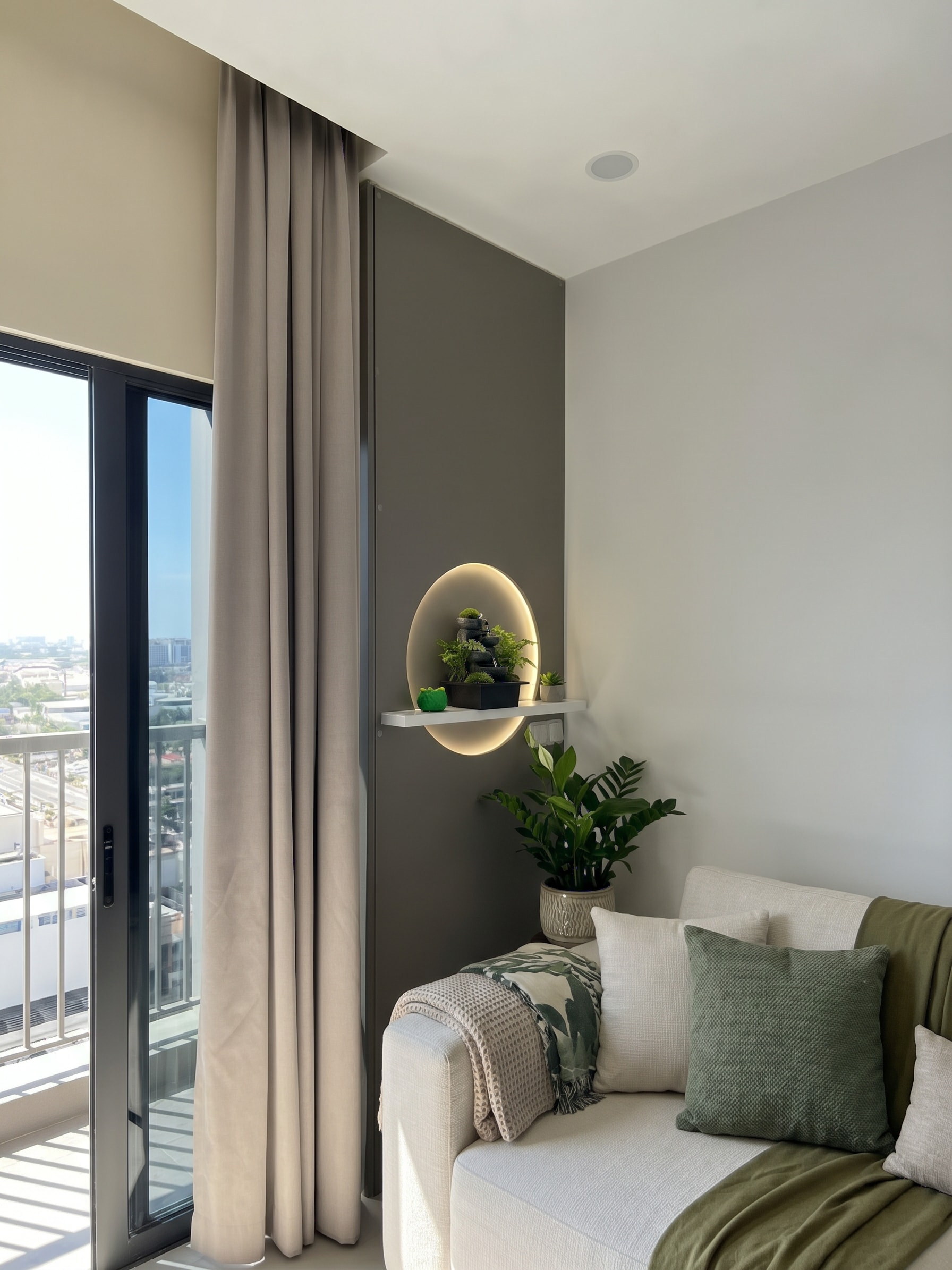 Living room sofa corner with custom partition featuring circular LED niche and plants
