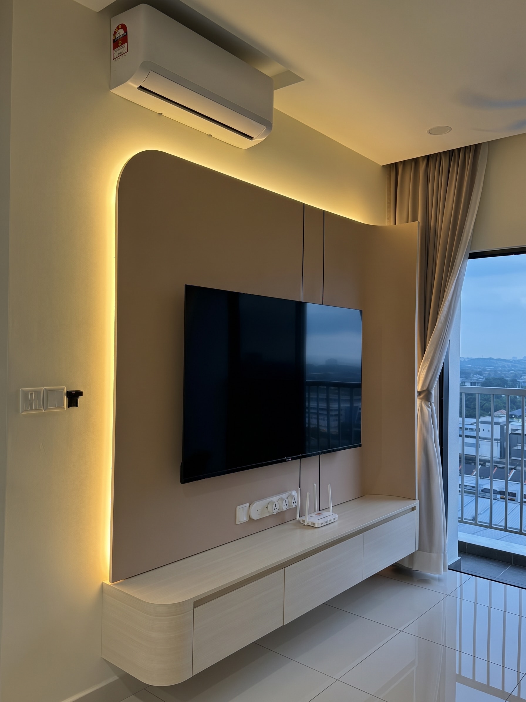 Curved TV wall panel with warm perimeter LED backlighting and floating console