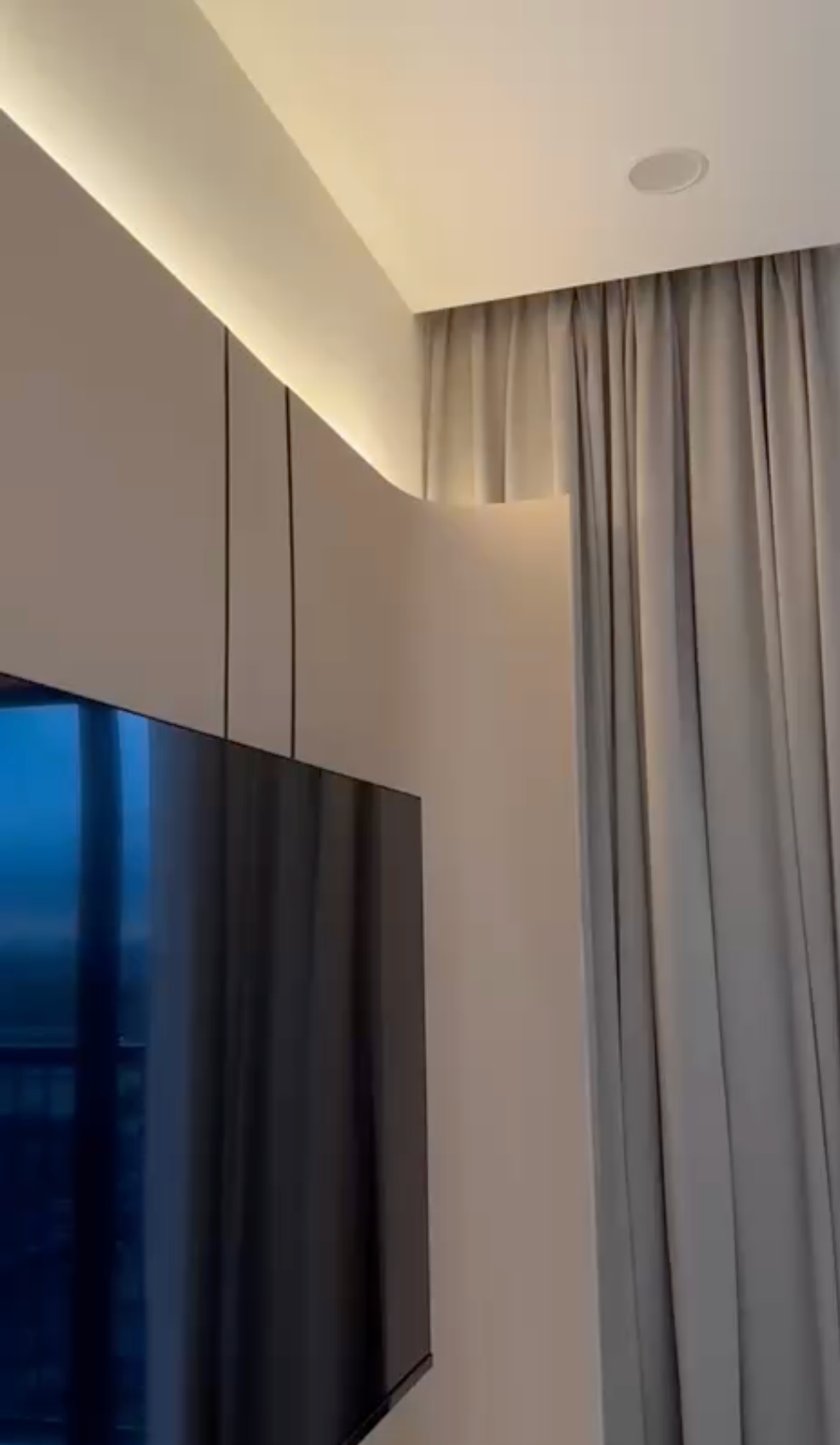 Curved TV wall panel close-up showing cove ceiling LED and curtain detail
