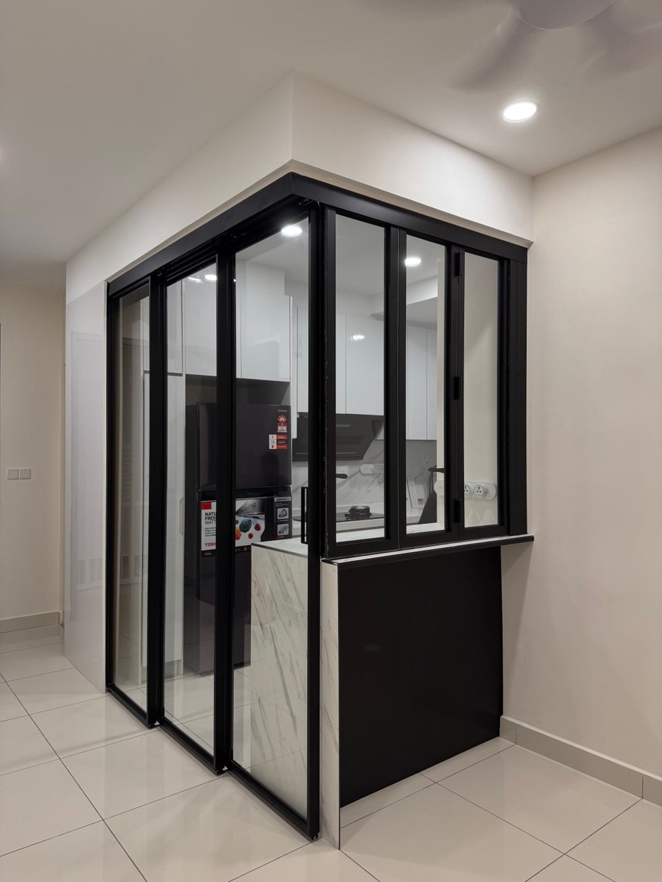 3-panel black-framed glass pocket door system closed, enclosing the kitchen