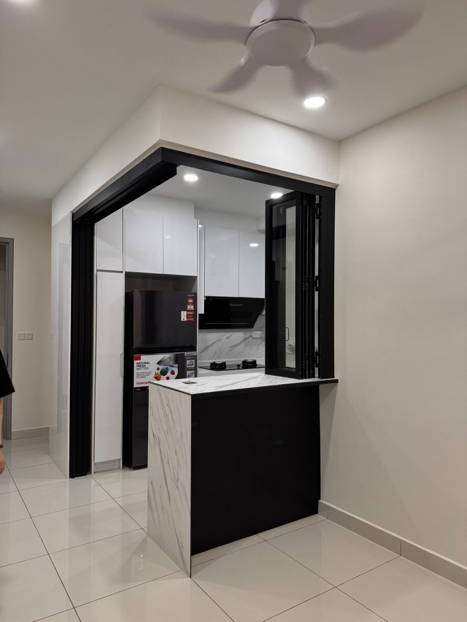 Kitchen with glass pocket doors open, marble-effect island, and white cabinetry