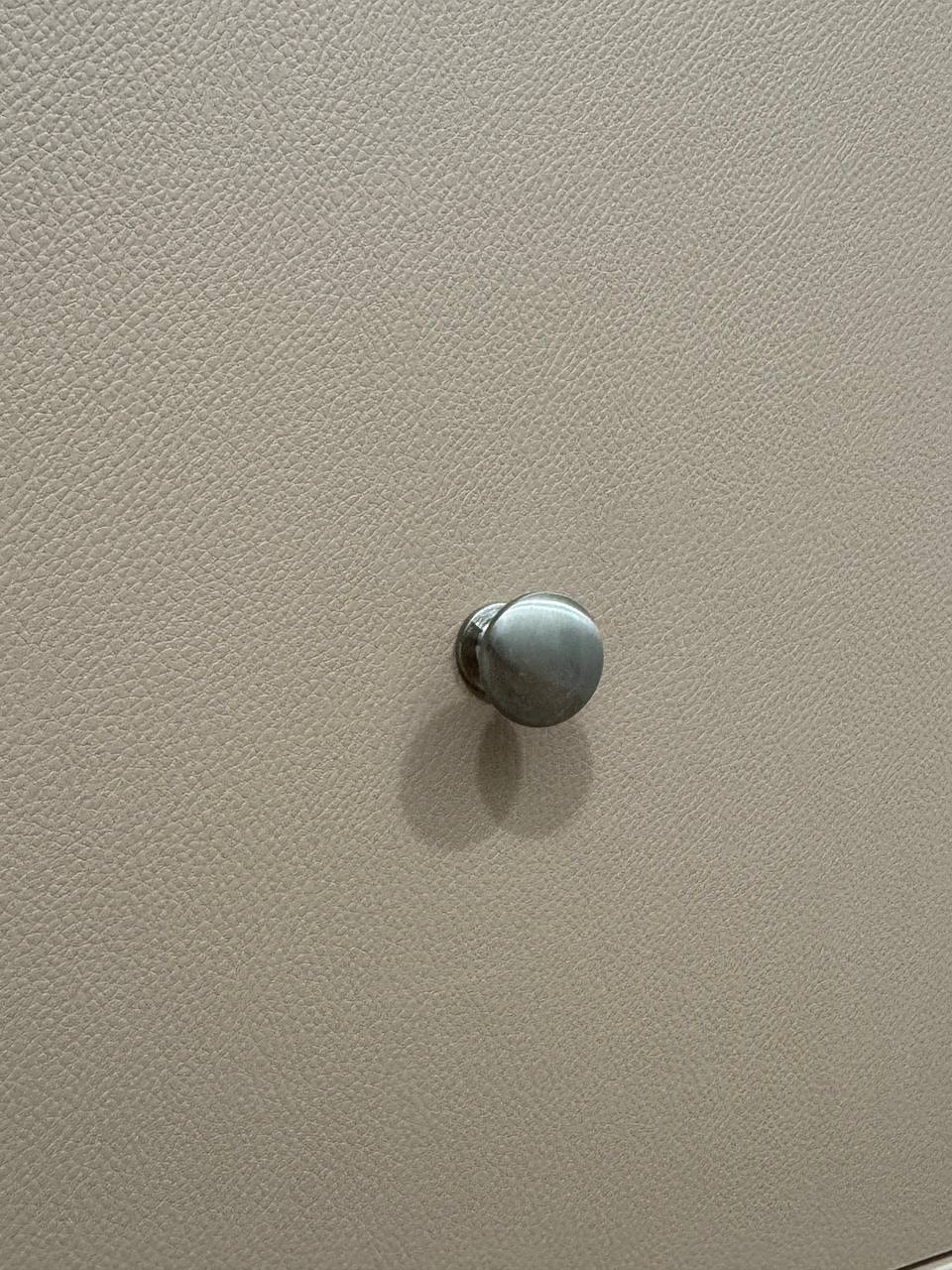 Close-up of brushed chrome cabinet knob on leather-finish panel