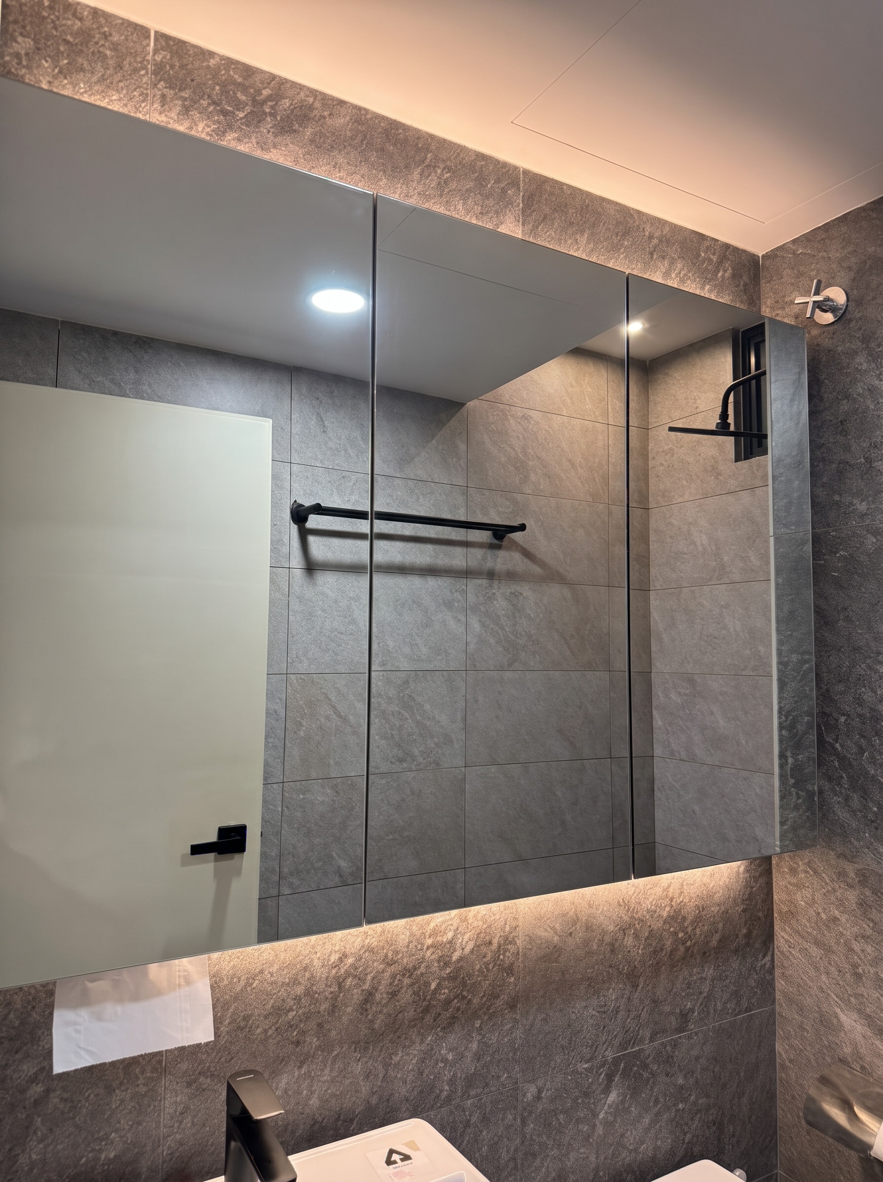 Master bathroom with full-height mirror, grey stone tiles, and black fixtures