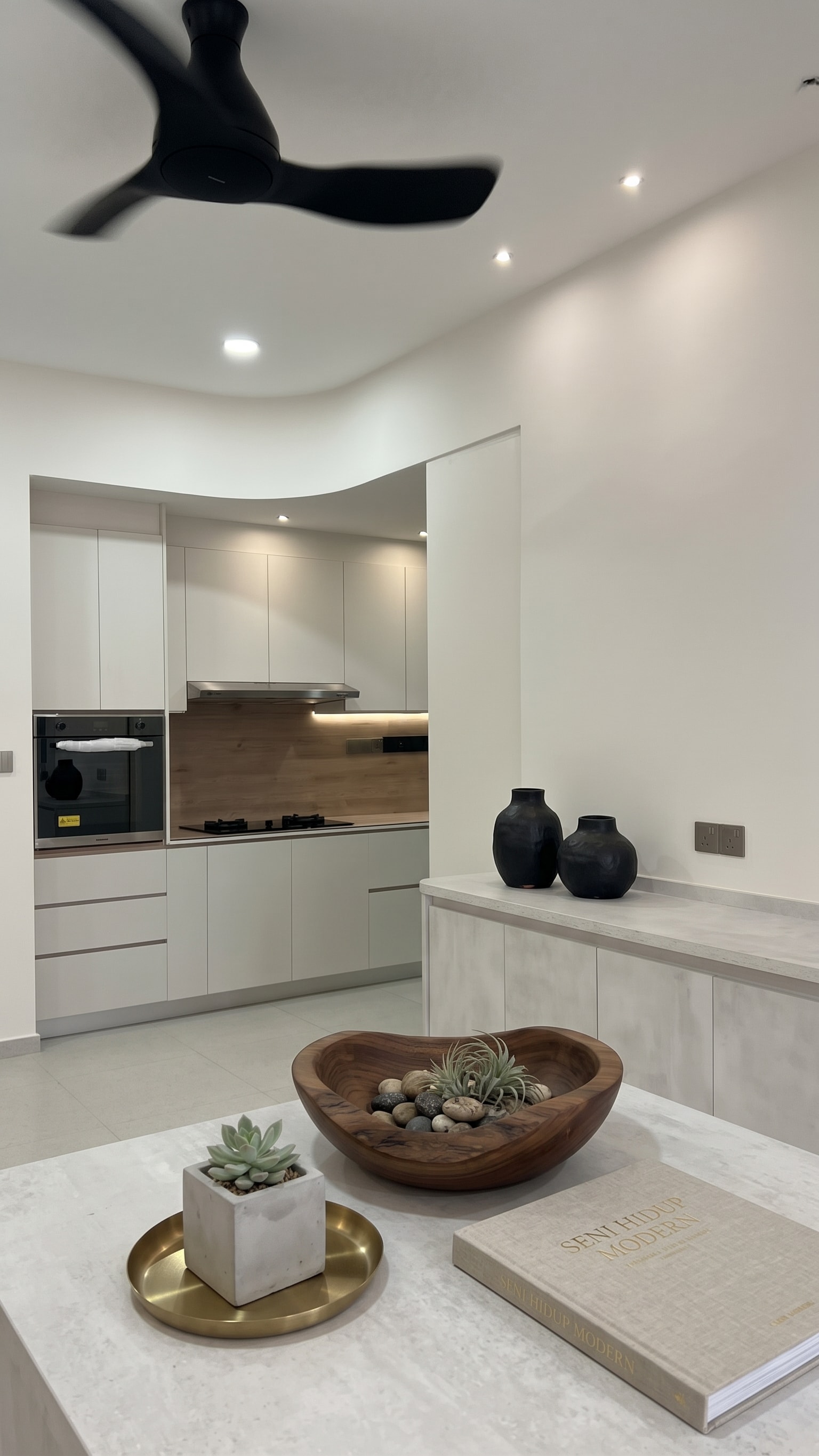 Open-plan kitchen and dining area with round-edge pantry cabinet and black ceiling fan