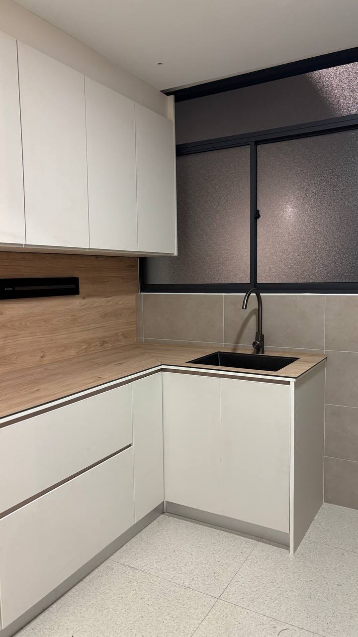 Kitchen sink corner with wood grain backsplash and black matte tap