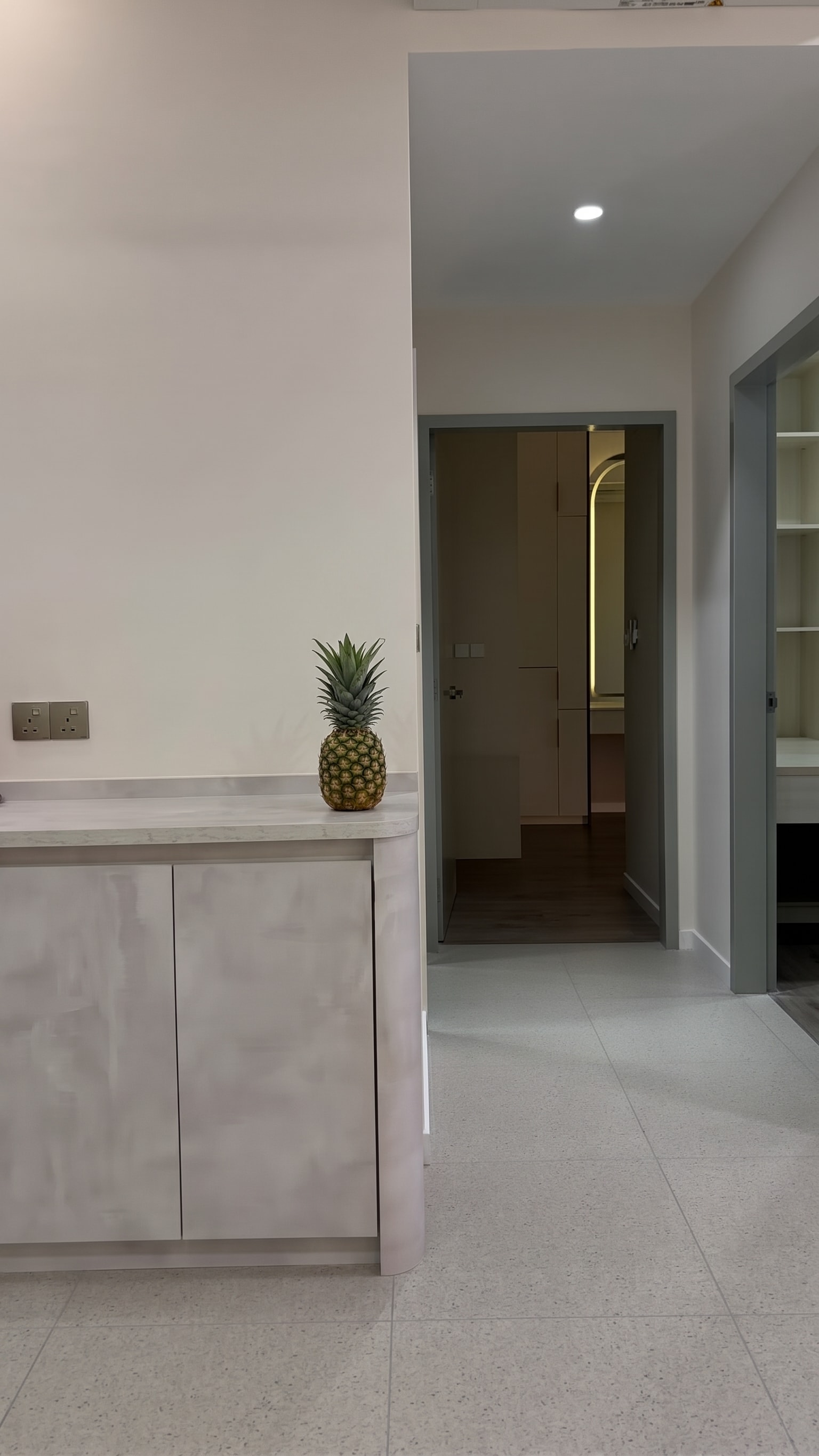 Round-edge pantry bottom cabinet beside dining area with hallway view