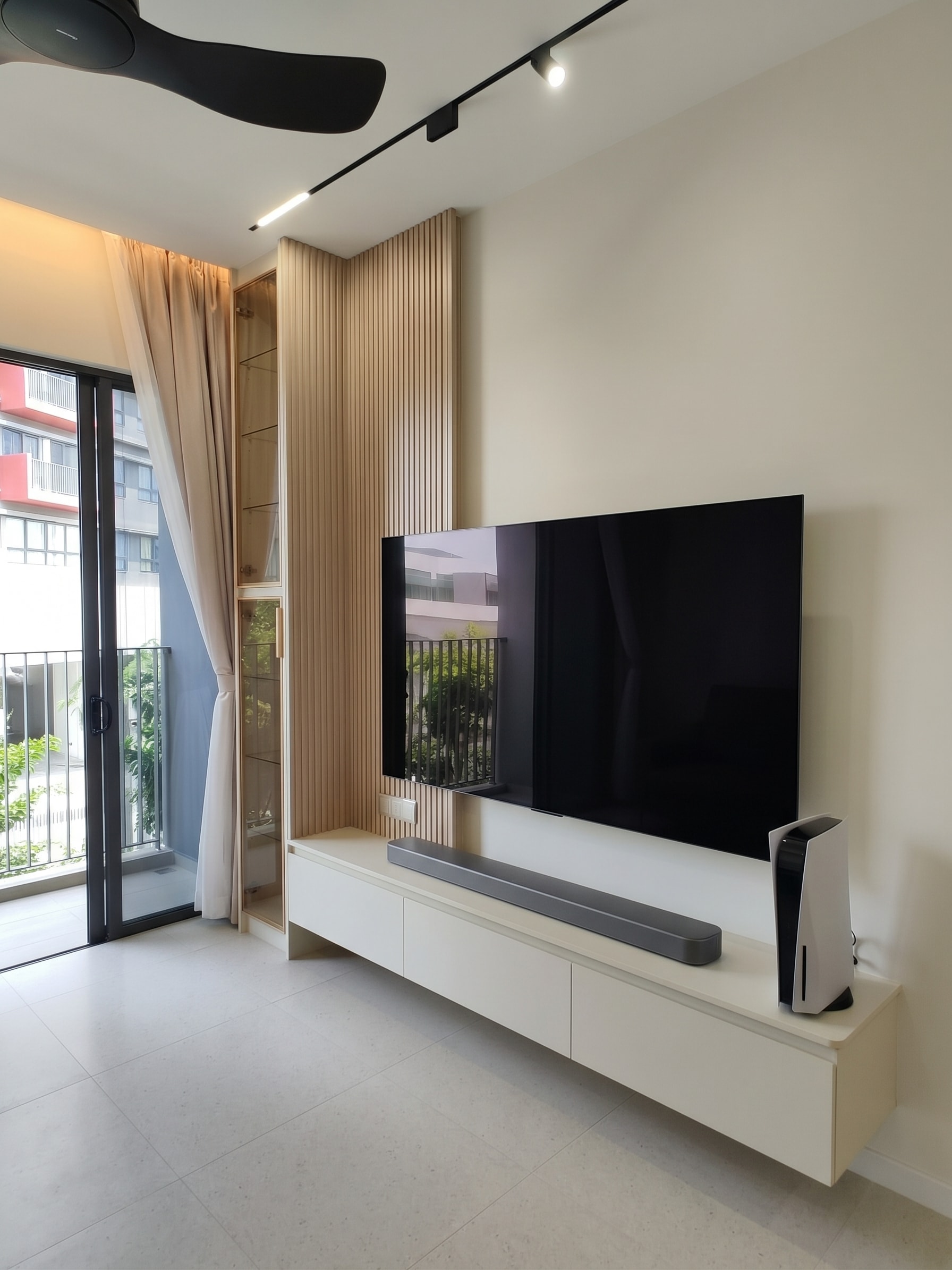 Living area with TV console, fluted half-wall panel and glass display cabinet